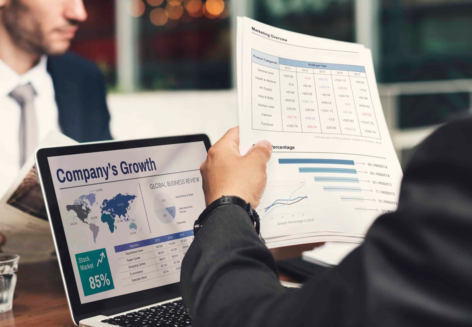 Businessman analyzing company growth charts and financial reports on laptop and printed documents.