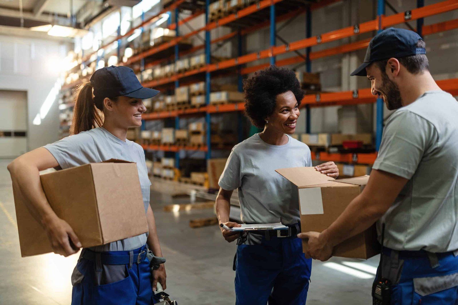 Happy warehouse employees examining packages together inside a distribution center