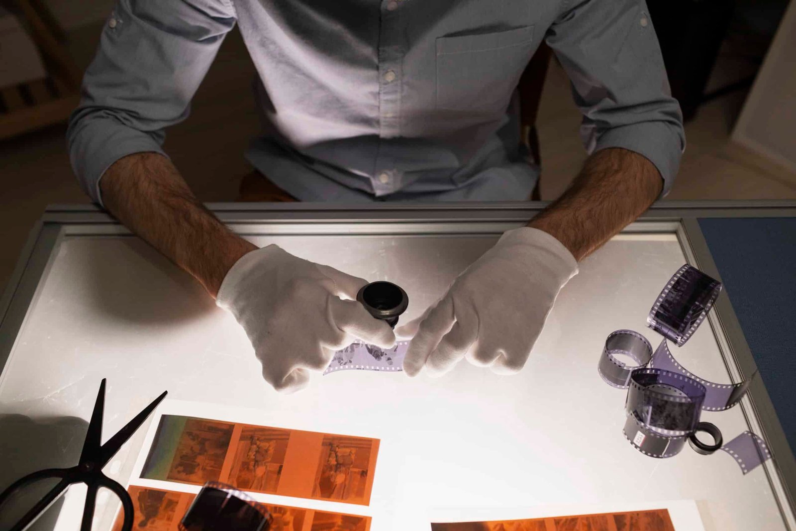 Technician examining photographic film negatives on light table